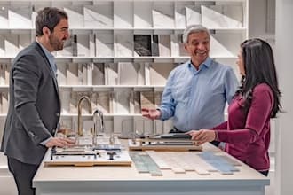 A showroom assistant helps an older couple choose tile, fixtures, and hardware for their renovation.