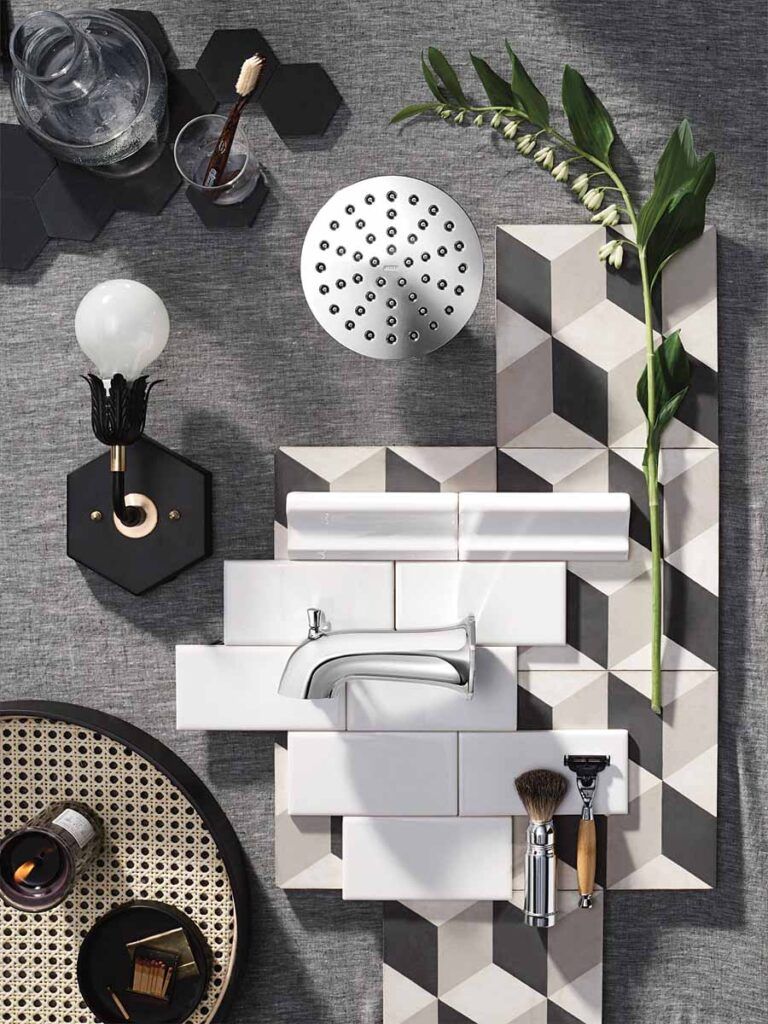 A designer's flat lay of various shower parts and tile, including a tub spout and showerhead.