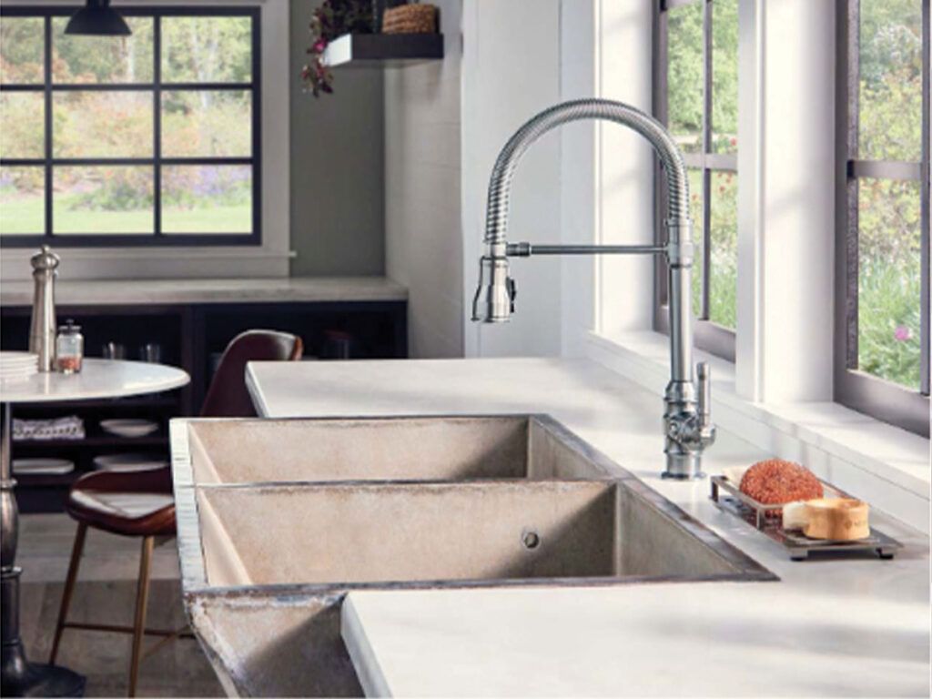 An industrial style concrete kitchen farmhouse sink paired with a chrome Delta Broderick faucet.