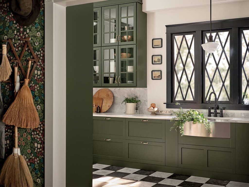 A demure green and black kitchen with a stainless steel farmhouse sink.