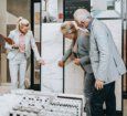 A tile expert shows an older couple marble tile options for their bathroom renovation in a Studio41 showroom,