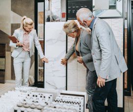 A tile expert shows an older couple marble tile options for their bathroom renovation in a Studio41 showroom,