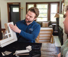A male window expert giving a homeowner an in-home estimate on their replacement window options.