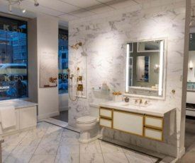 Interior shot at Kohler Hubbard of a bathroom display with floating vanity, toilet, bathtub, shower, and lighted mirror