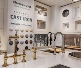 Angled shot of Kohler Hubbard's stainless steel sinks and many faucets