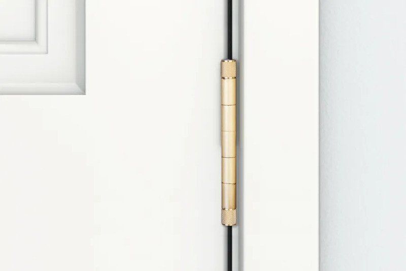 View of a brass Emtek hinge on a white door and doorframe