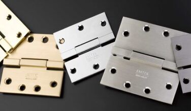 Various Emtek hinges in different finishes on a black background, including both residential and heavy duty hinges from Emtek.