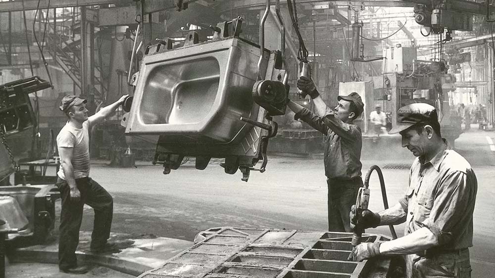 an old black and white photo of the kohler factory, two workers manufacturing a tub