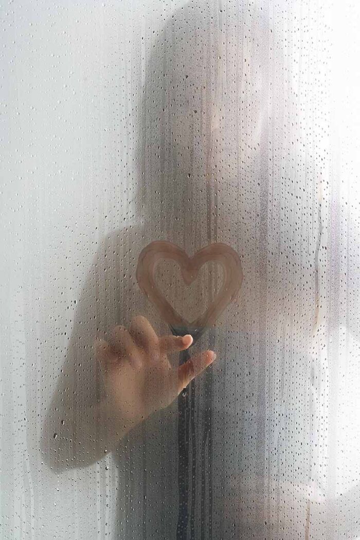 a woman drawing a heart in the steam of her mr steam shower