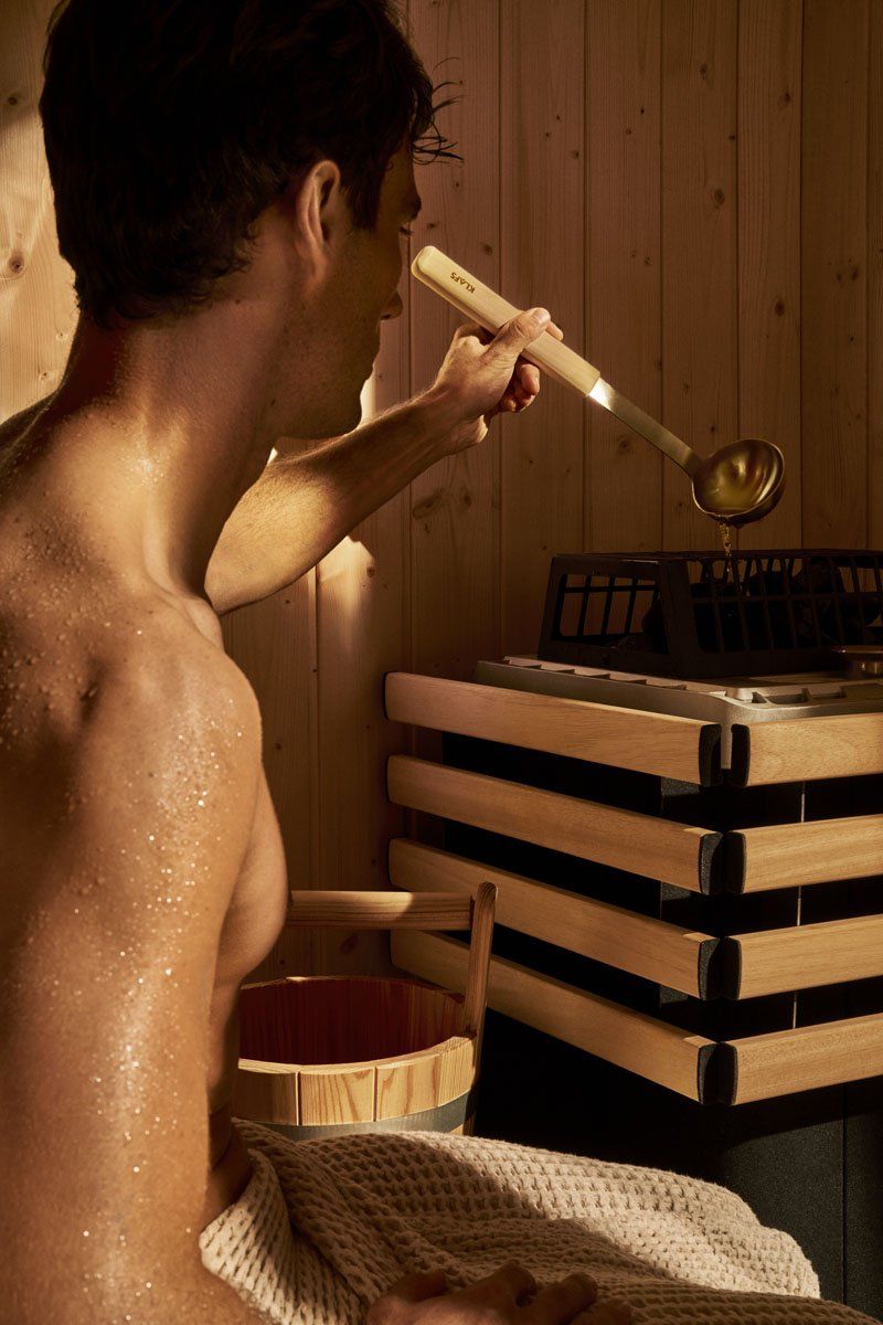 a sauna enjoyer adding water to increase his sauna's humidity