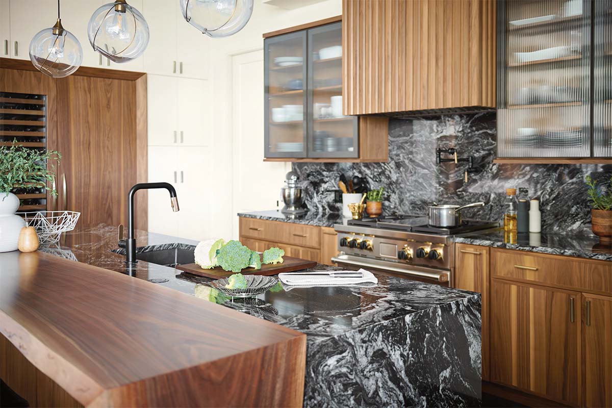 A modern and striking kitchen featuring Omega cabinetry Jax cabinets, quartz countertops and backsplashes, and black and gold duotone fiixtures and lighting.